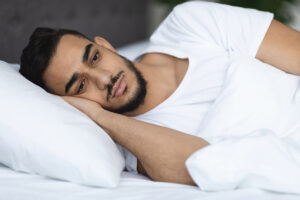 Sleep Disorders. Closeup Shot Of Upset Arab Man Lying In Bed With Open Eyes, Portrait Of Pensive Young Sad Middle Eastern Guy Suffering Insomnia While Relaxing In Bedroom At Home, Closeup Shot