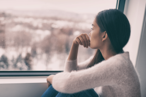Woman stares out window and ponders if she should take medication for depression