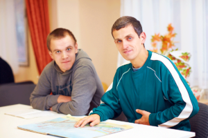 Two men look at camera as they prepare documents for autism awareness month