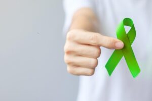 Woman holds up green ribbon to represent mental health awareness month