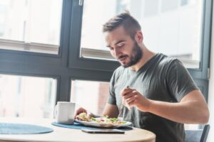 Man sits at dinner table and eats, pondering the connection between OCD and eating habits