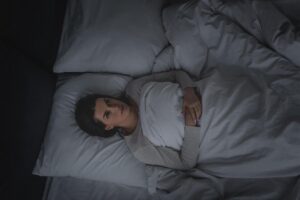 Person lays awake in bed wondering about their sleep and mental health
