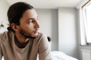 Man sits on bed and wonders what is dysthymia