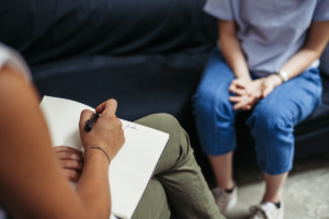 Therapist takes notes as she instructs client how to prepare for their first therapy session