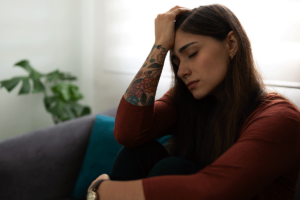 Woman dealing with traumatic grief struggles while sitting on couch