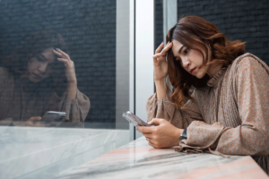 Woman looks at phone as she struggles with anxiety and social media posts