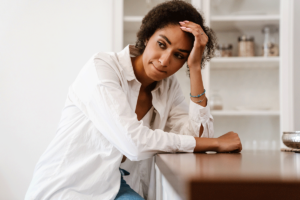 Woman sits at kitchen counter and thinks about the link between OCD and ADHD