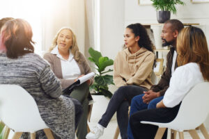 a group of people sit and are talking about benefits of mental health treatment as a group