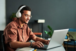 man with headphones is on laptop searching for online therapy in seattle