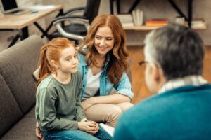 mother and child sit with a specialist to learn more about autism spectrum disorder