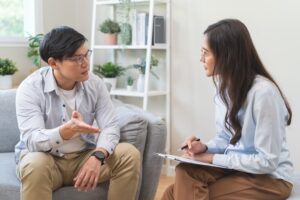 therapist sits with clipboard listening to patient discuss his concerns about depressive disorders