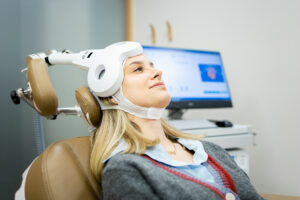 woman sits in a chair while undergoing tms treatment